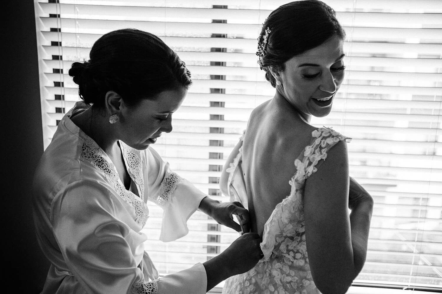 sister helping the bride with dress